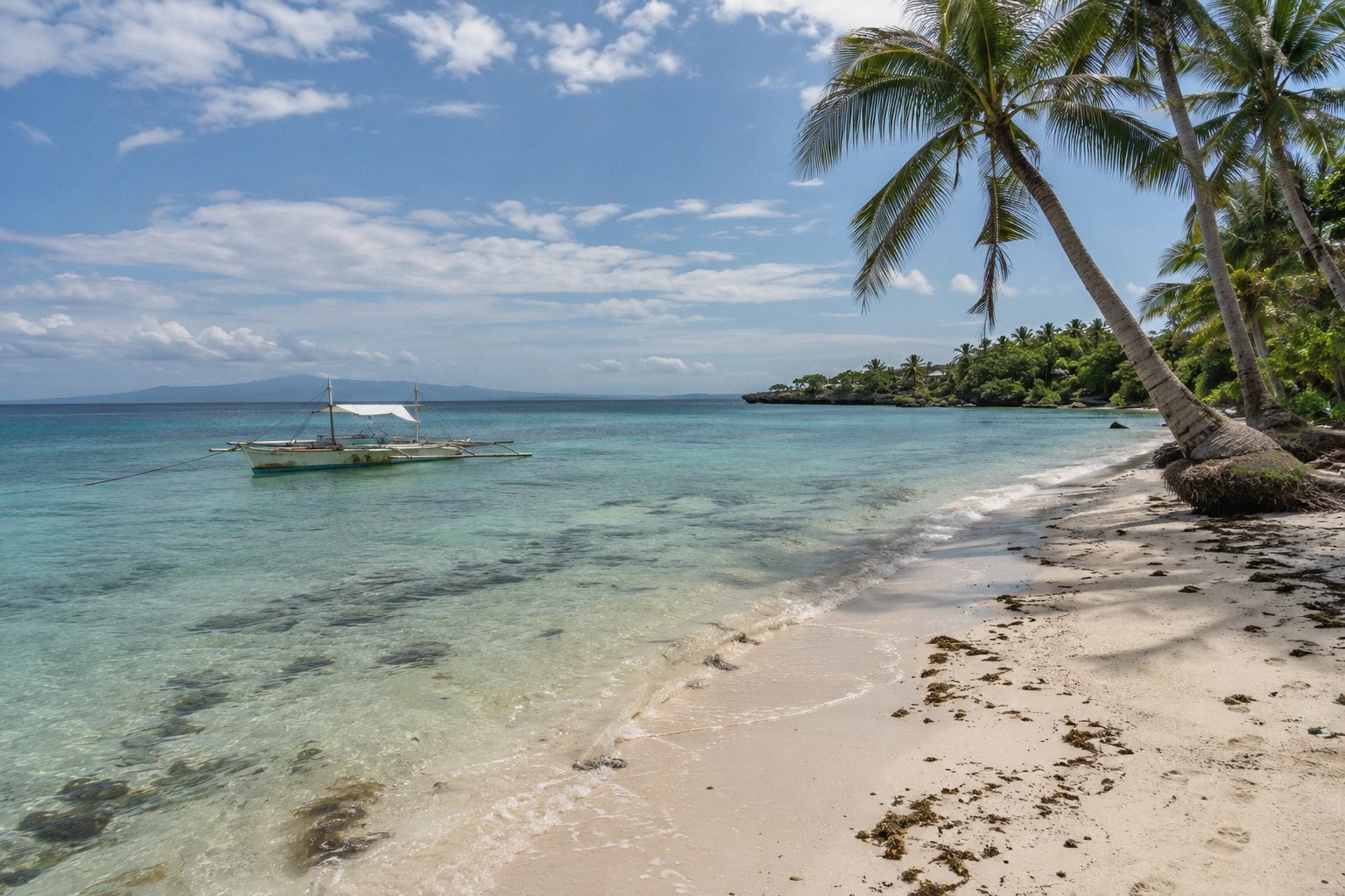Quiet white-sand beach on Panglao with a traditional bangka boat